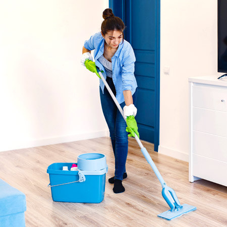 professional house cleaner mopping wood floors in green gloves