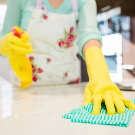 professional house cleaner wiping counter with green and white cloth
